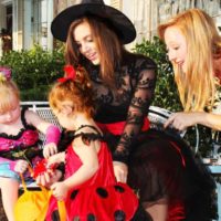 Little girls and their mothers inspect Halloween candy