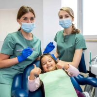 Pediatric,Female,Dentist,With,Assistant,With,Child,Girl,Patient,Showing